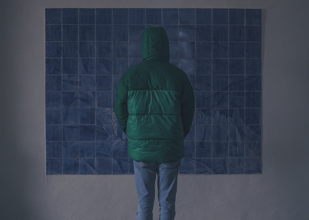 a person standing in front of a blue tiled wall