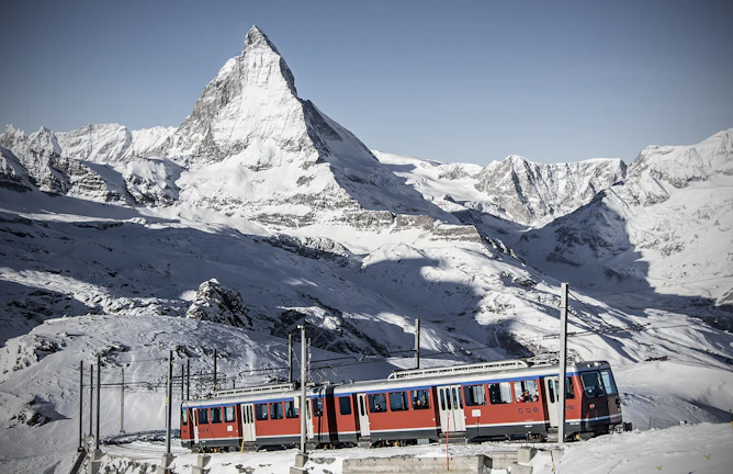 A panoramic view of the Bernina Express winding through snow-covered Swiss Alps.