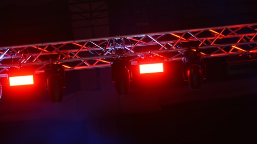 Close-up of hands securing truss connections under bright event lights, showcasing precision and care.