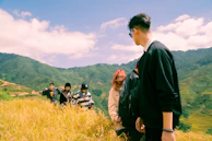 A group of young travelers laughing together on a scenic hike in Ella, surrounded by lush green hills.