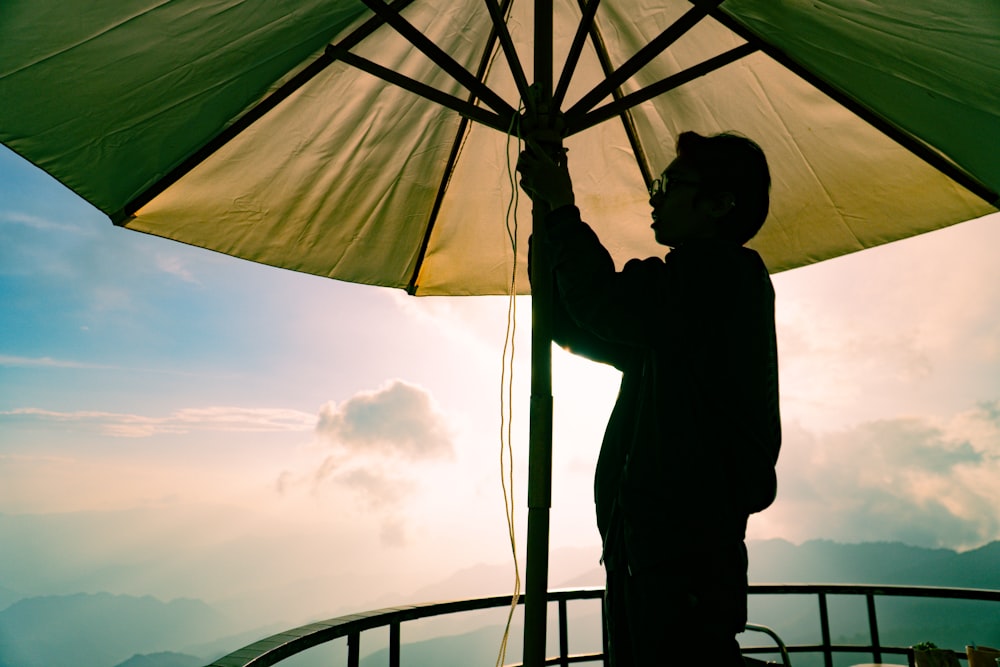 a man holding an umbrella on top of a mountain