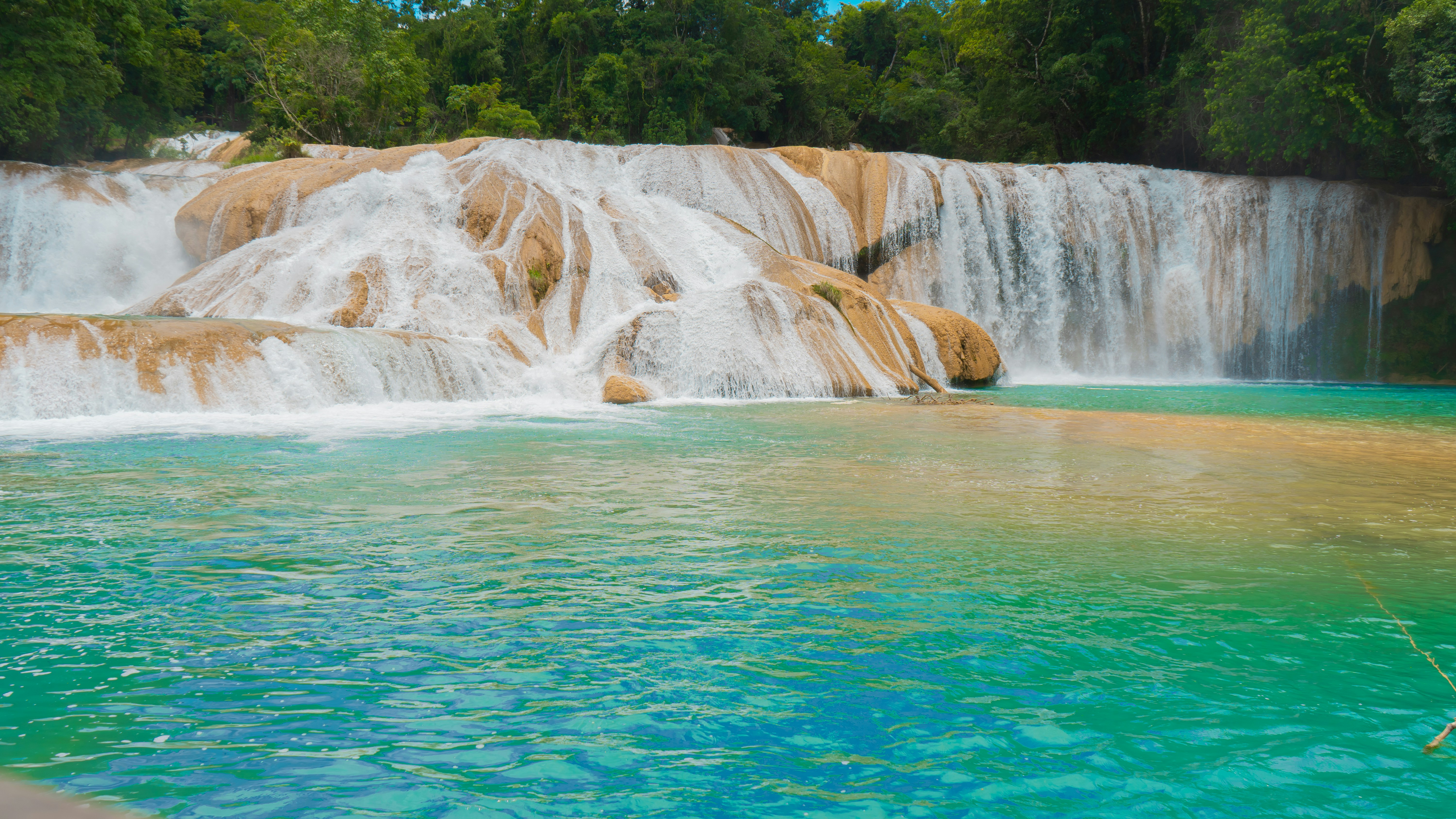 a large waterfall with a blue pool in front of it