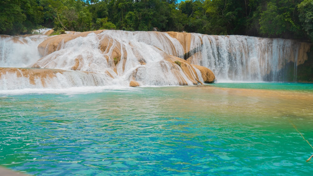 a large waterfall with a blue pool in front of it