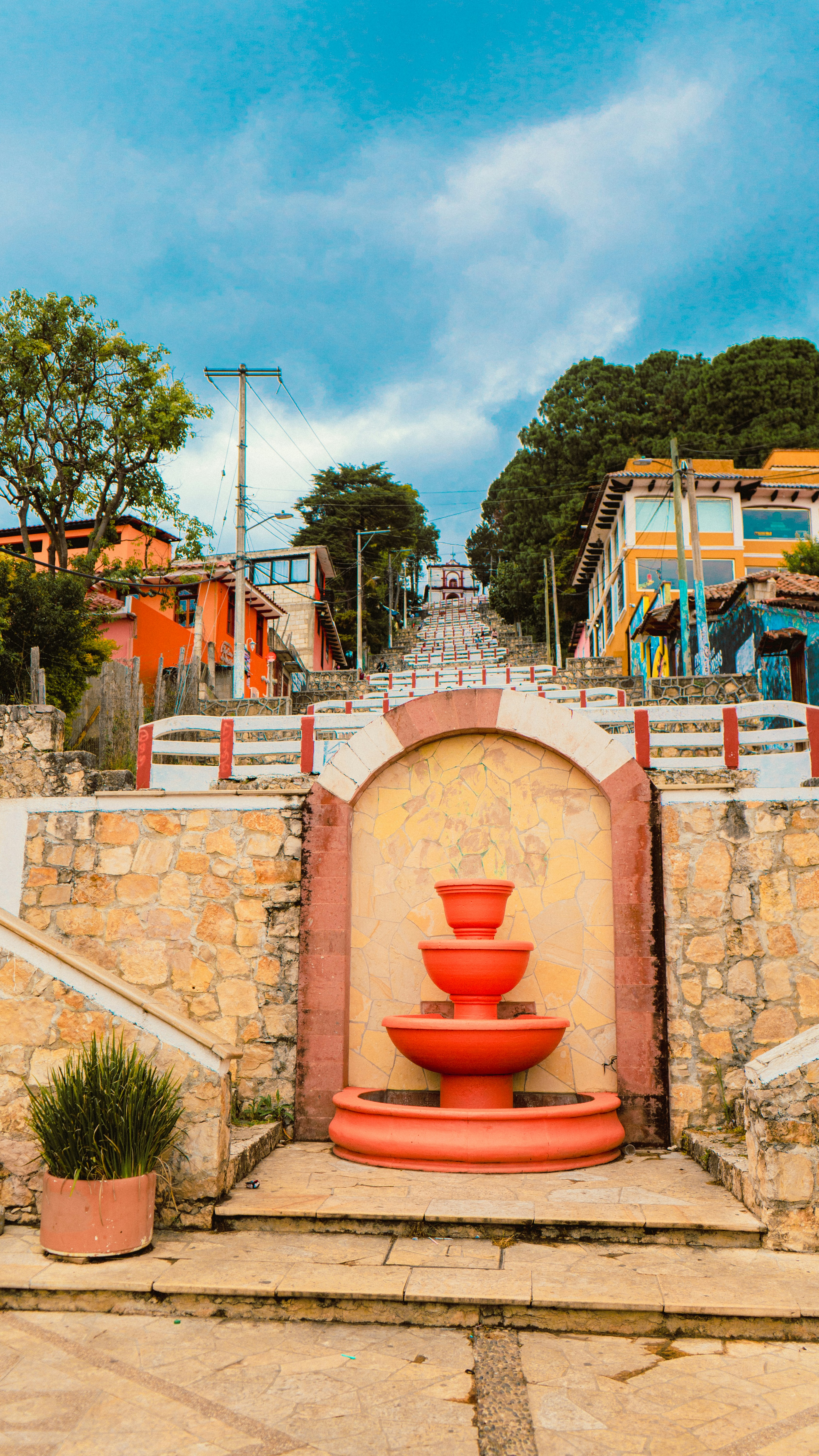 a red fountain sitting in front of a stone wall
