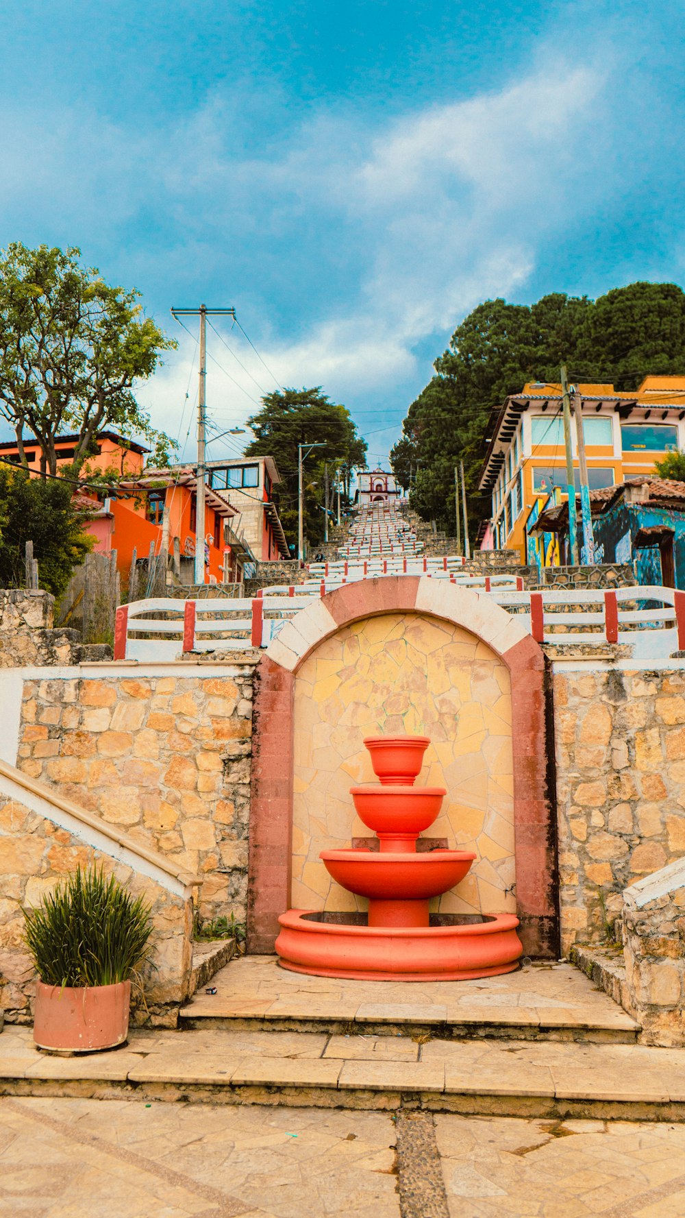 a red fountain sitting in front of a stone wall