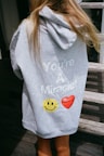 a little girl wearing a sweatshirt with a smiley face on it