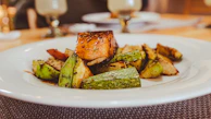 A skillet sizzling with golden-brown seared salmon and a side of roasted seasonal vegetables.