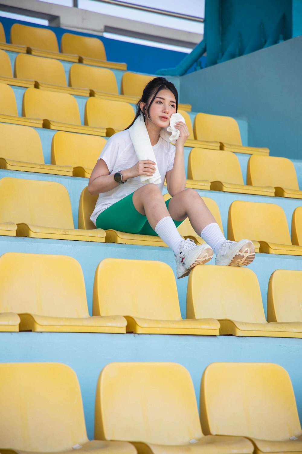 a woman sitting on the bleachers eating a donut