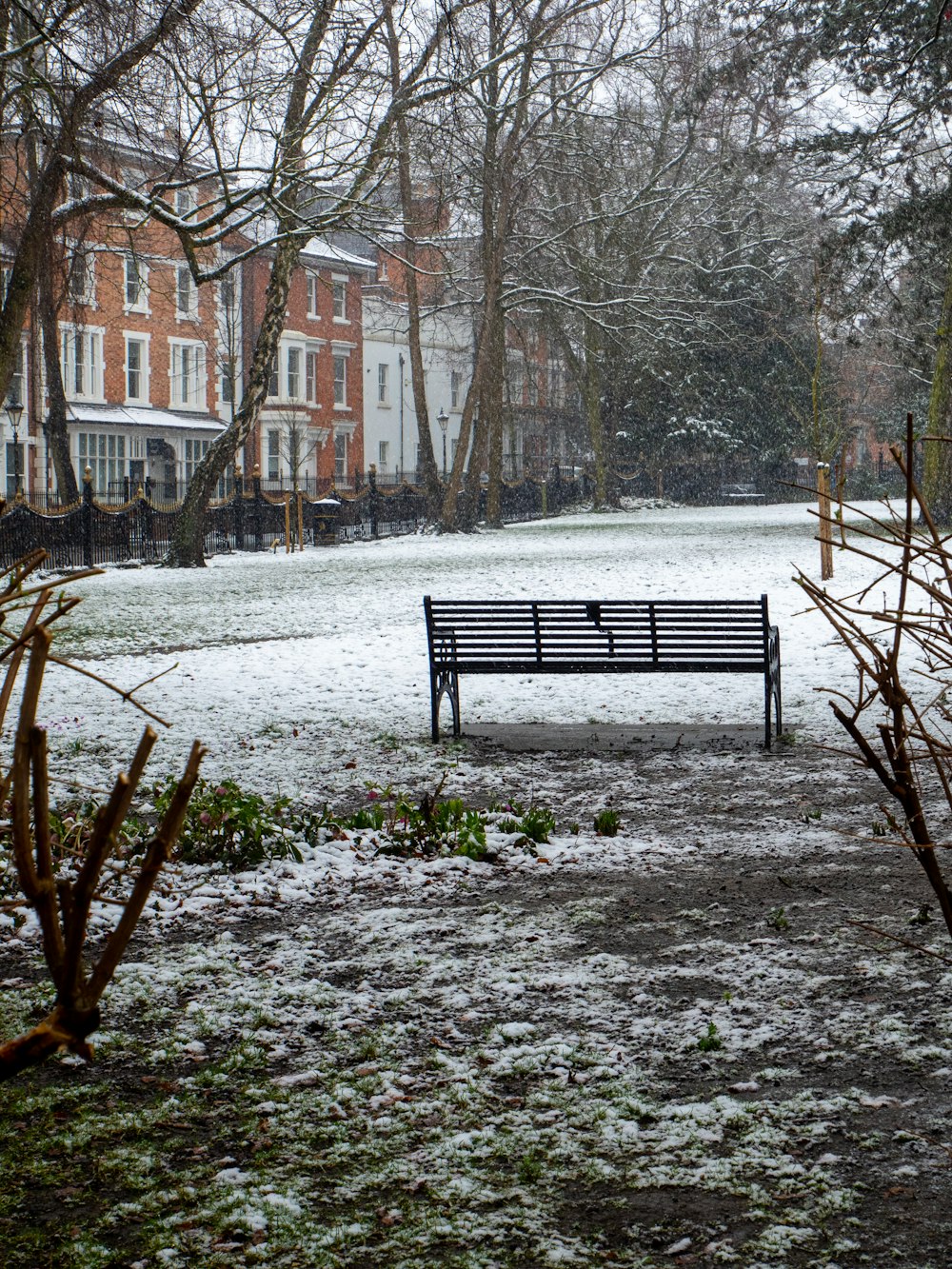 a bench sitting in the middle of a park covered in snow
