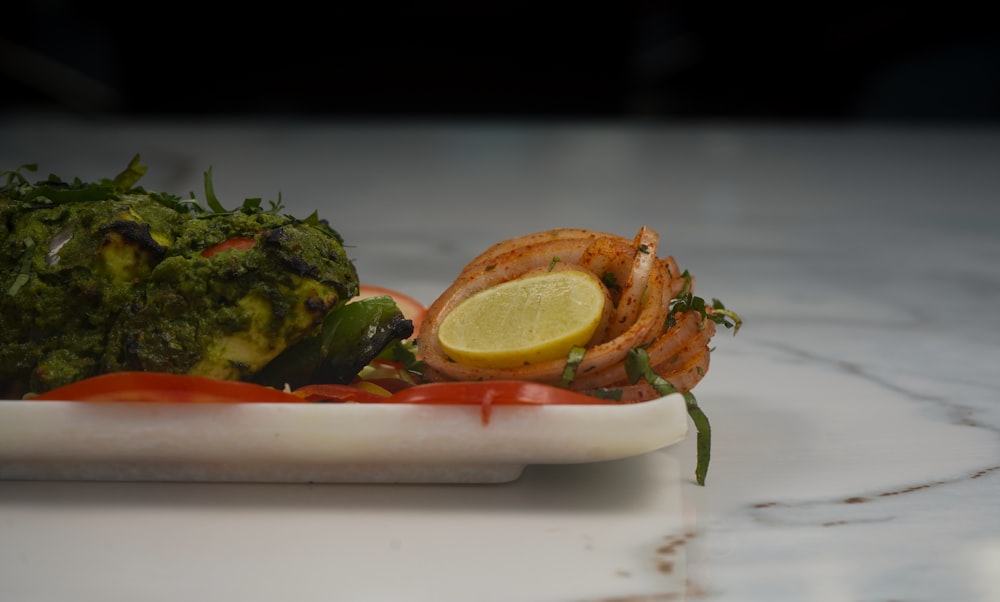 a plate of food with shrimp, broccoli and a lemon wedge