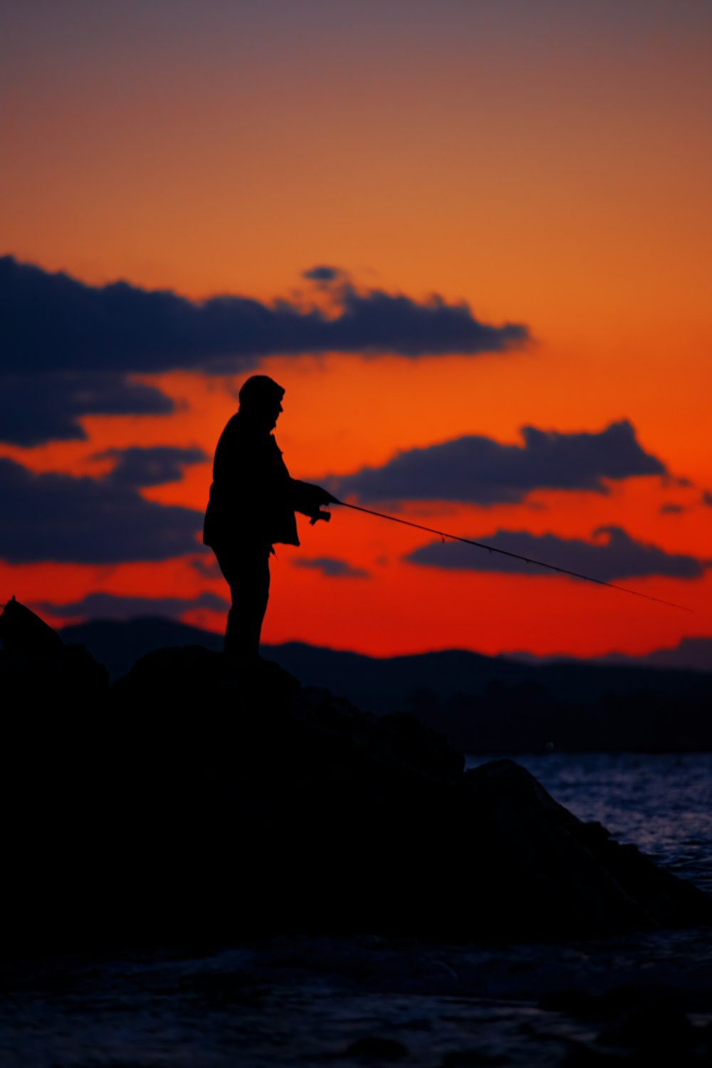 a silhouette of a man fishing at sunset