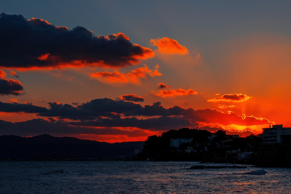 the sun is setting over the water with a boat in the foreground