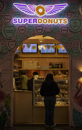 a woman standing in front of a doughnut shop