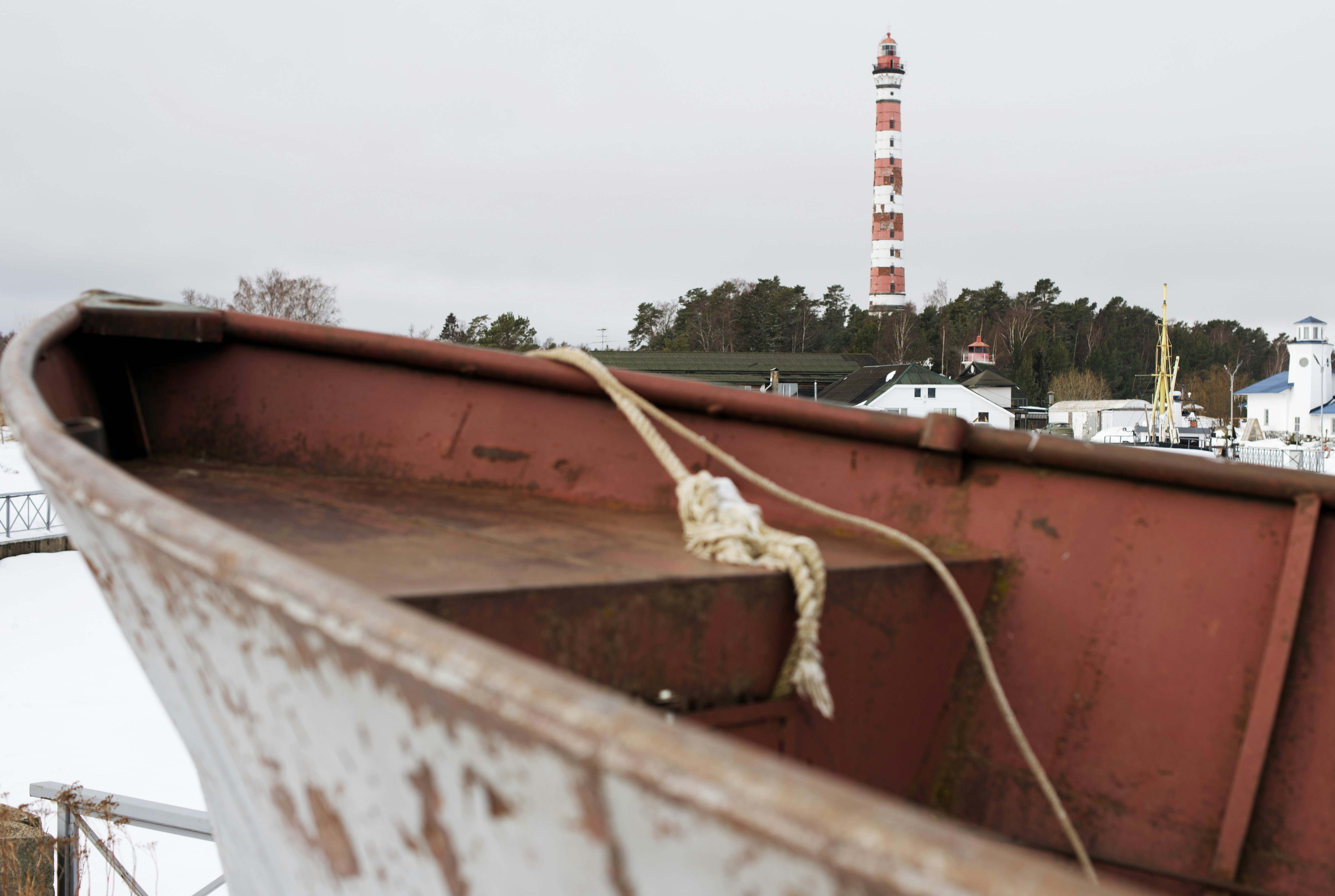 a rusted boat with a lighthouse in the background