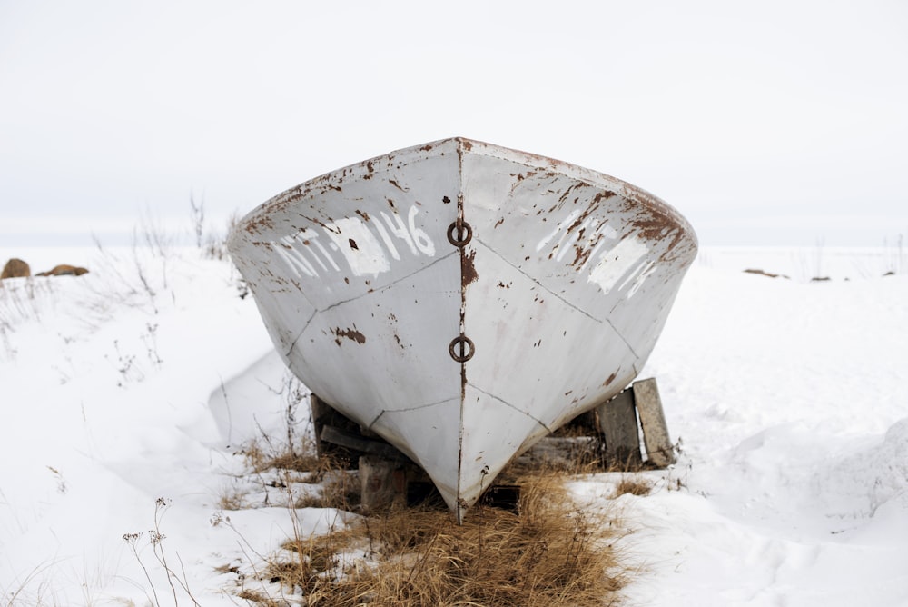 a white boat sitting on top of snow covered ground