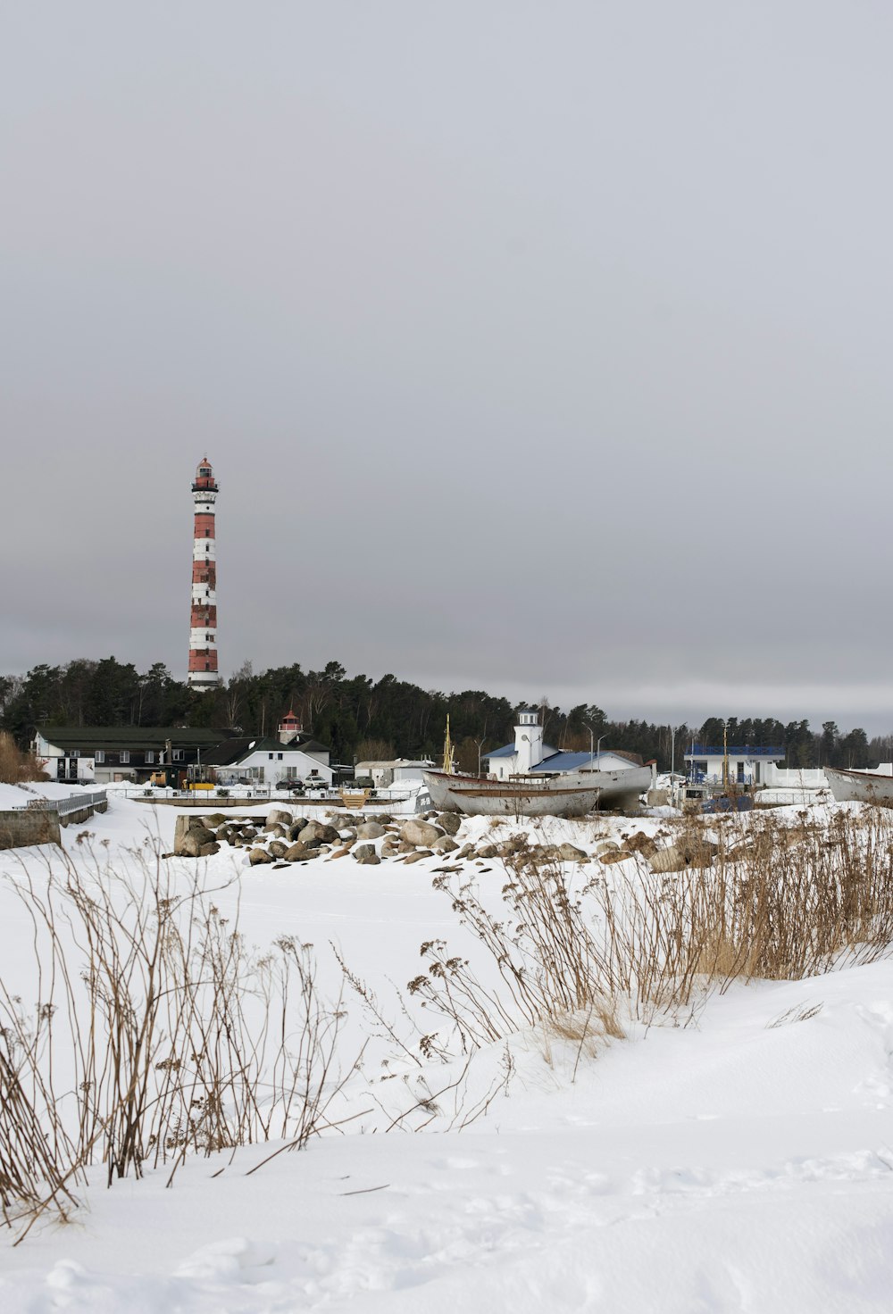 a lighthouse in the distance with snow on the ground