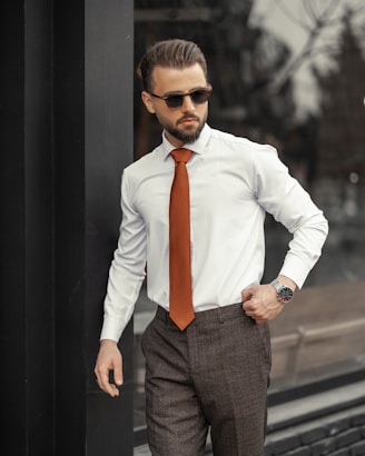 A well-dressed man adjusting his tie in a stylish urban setting.