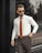 A well-dressed man in a stylish outfit standing confidently in an urban setting.