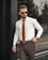 A well-dressed man in a stylish outfit standing confidently in an urban setting.