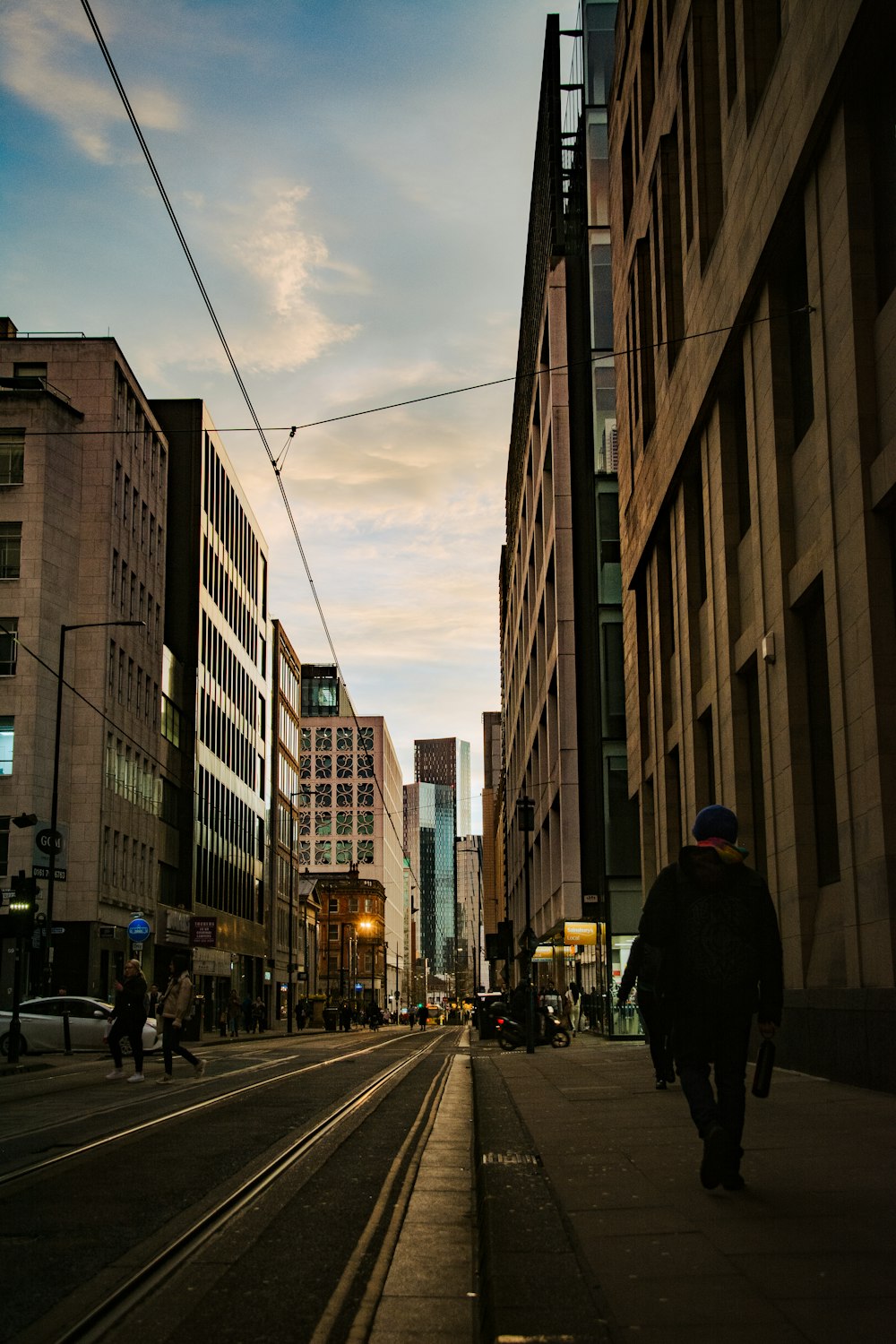 a man walking down a street next to tall buildings