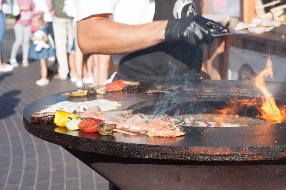 a man cooking food on a grill with flames