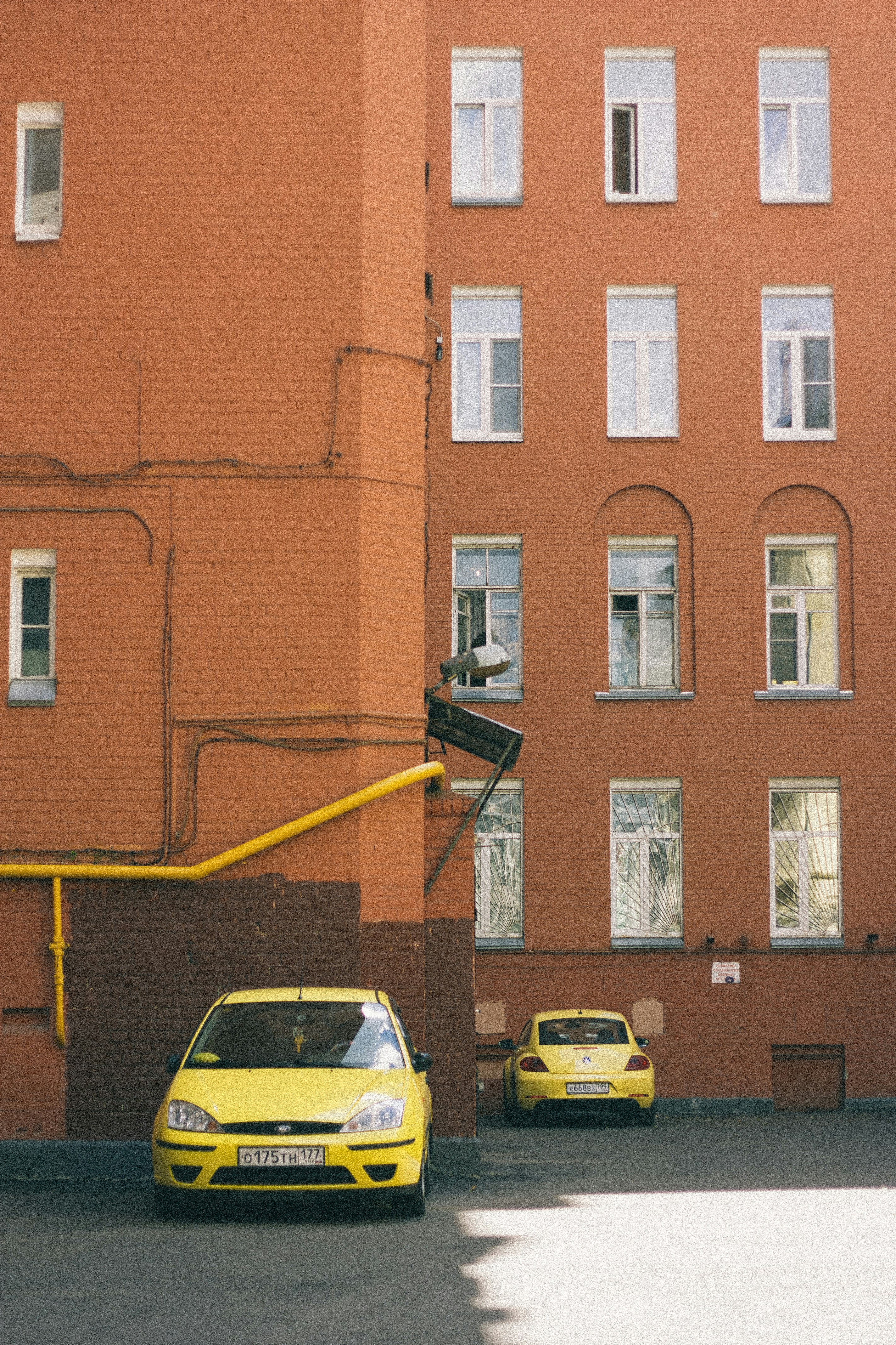 a yellow car parked in front of a tall brick building