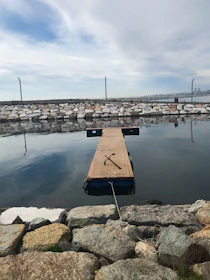 An anchor resting on a wooden dock with the ocean softly blurred in the background.