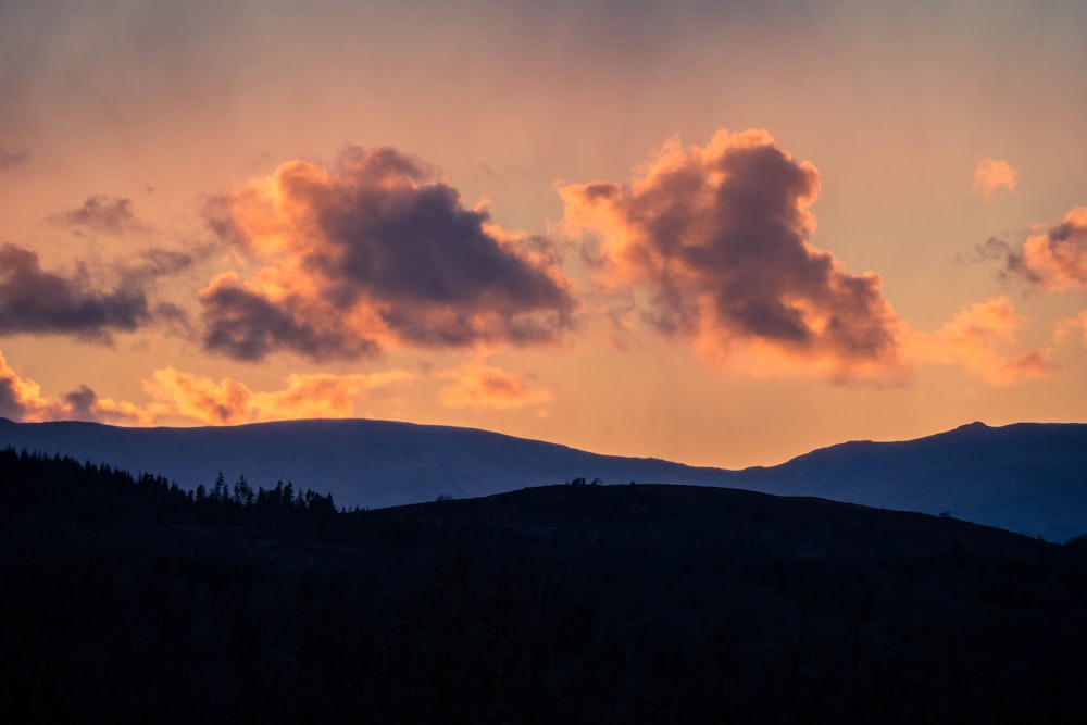 the sun is setting over a mountain range