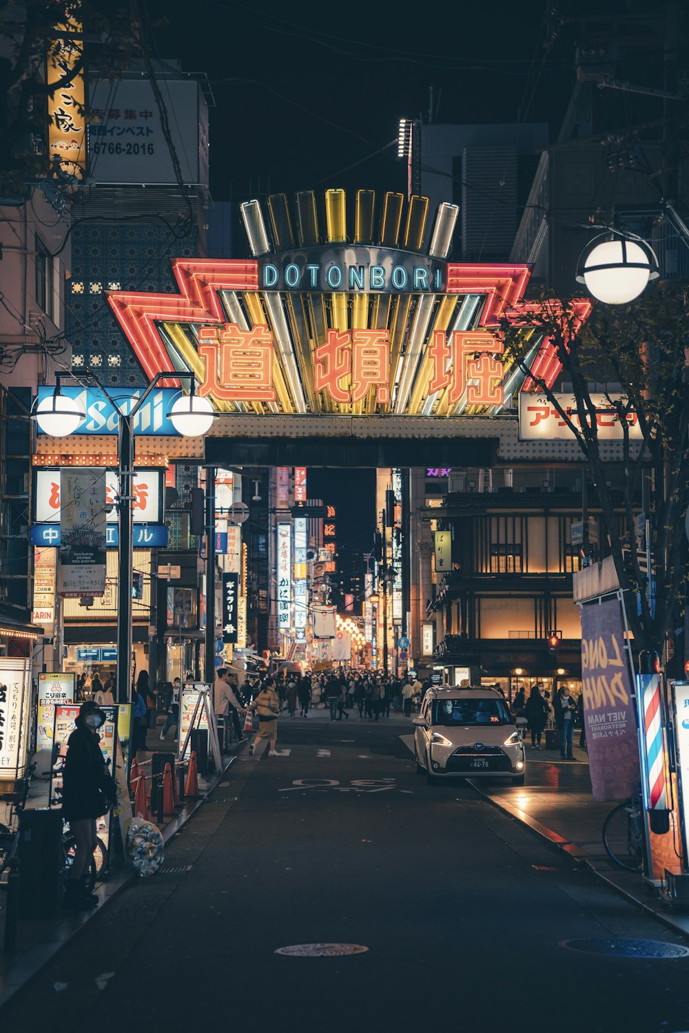 a city street at night with a neon sign above it