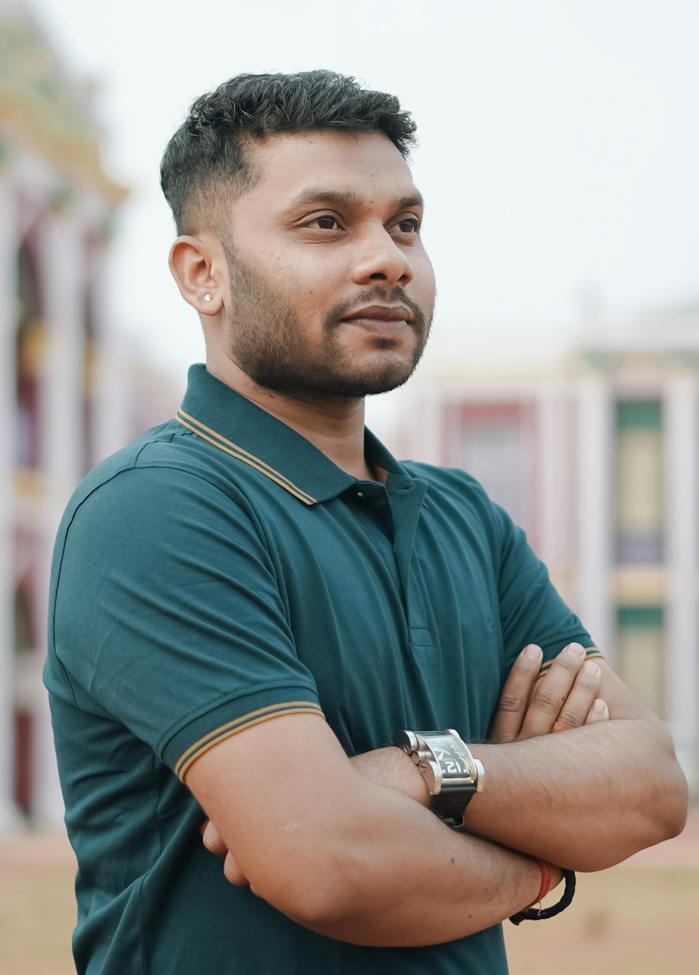 a man standing with his arms crossed in front of a building