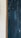 A close-up view of a textured surface featuring wooden vertical panels painted in a dark, weathered teal color. On the left, a small section of the wall with a rough, light-colored plaster finish is visible, bordered by a wooden frame.