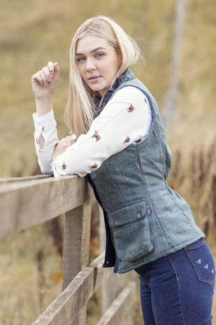 Julianna wearing a casual fall outfit with neutral tones, standing by a rustic wooden fence.