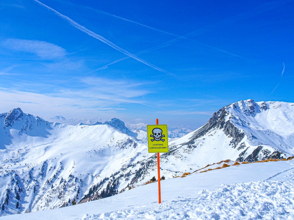 a sign in the snow with mountains in the background