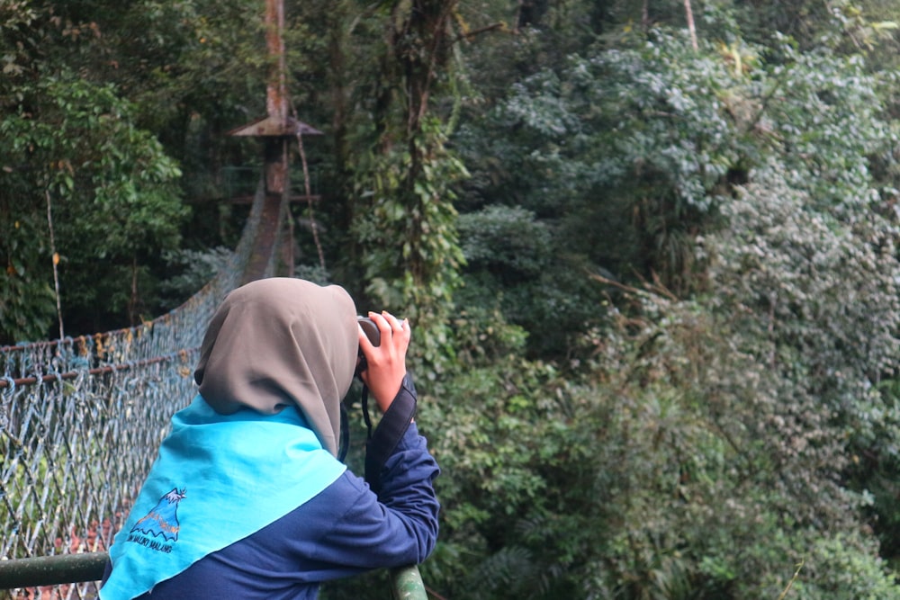 a woman standing on a bridge looking at the trees