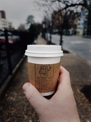 A close-up of a trendy cartoon figure holding a coffee cup on a busy sidewalk.