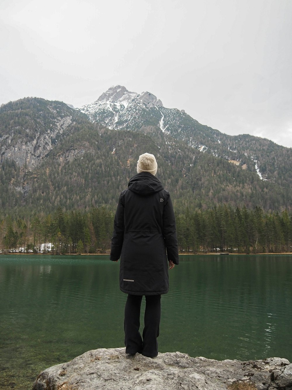 a person standing on top of a rock near a lake