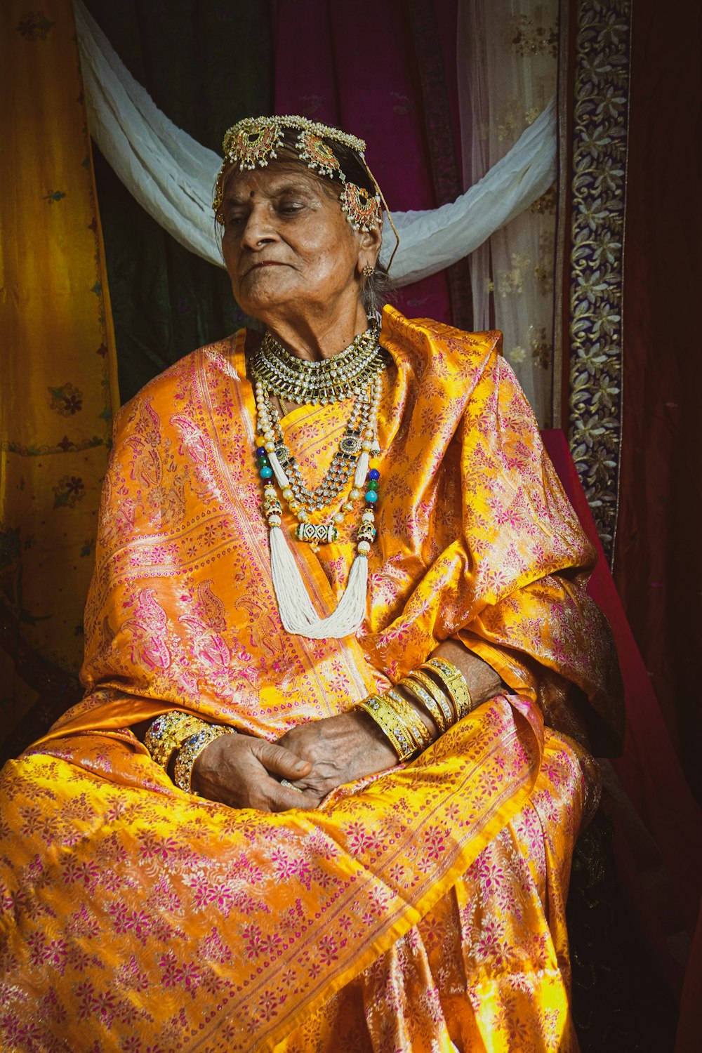 a woman in a yellow dress sitting in front of a curtain