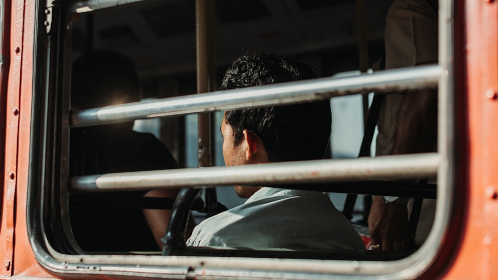 um homem sentado em um ônibus olhando pela janela