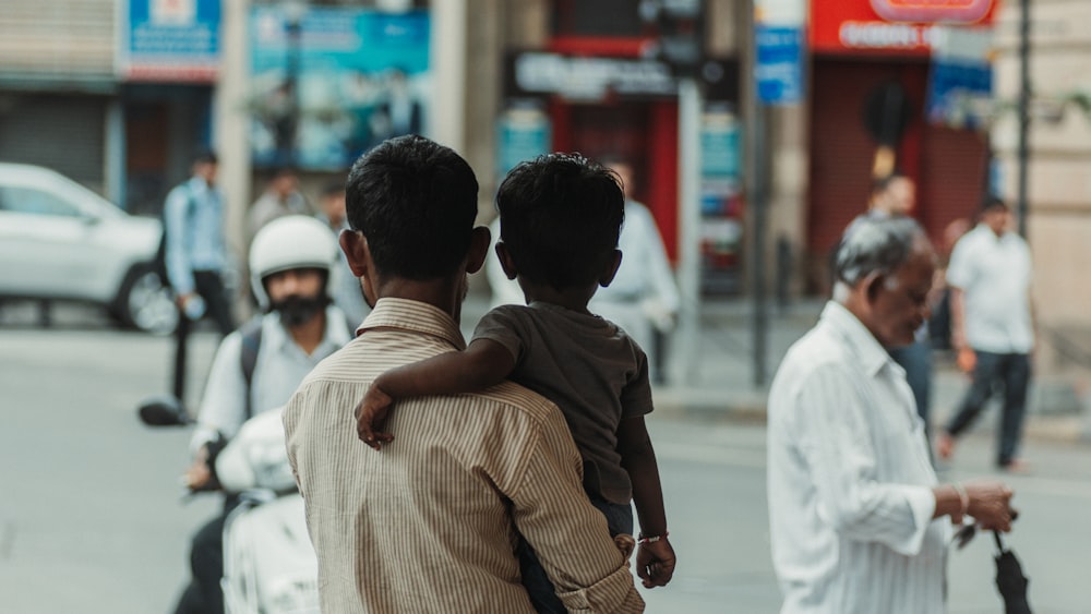 a man holding a child while walking down a street