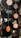Vinyl records of various sizes are hanging vertically, each suspended by a thin string. The records have labels in the center with different colors and text, mainly orange and black. They appear to be displayed artistically in an indoor setting with a blurred background.
