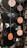 Vinyl records of various sizes are hanging vertically, each suspended by a thin string. The records have labels in the center with different colors and text, mainly orange and black. They appear to be displayed artistically in an indoor setting with a blurred background.