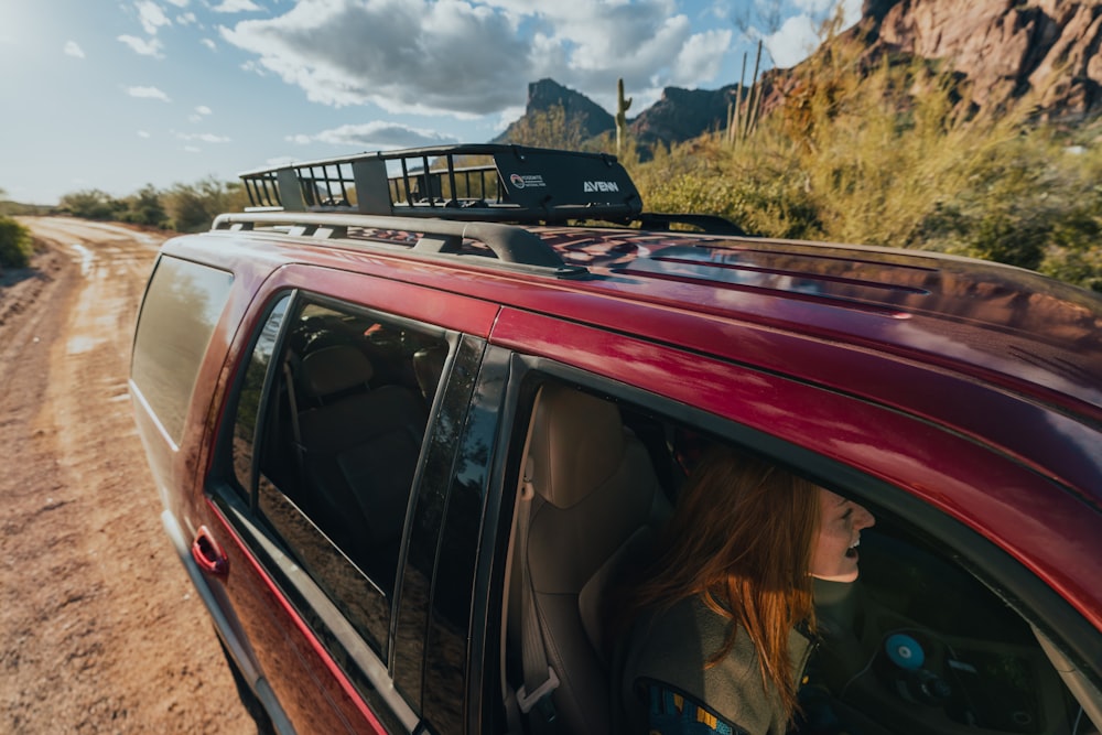 a red car driving down a dirt road