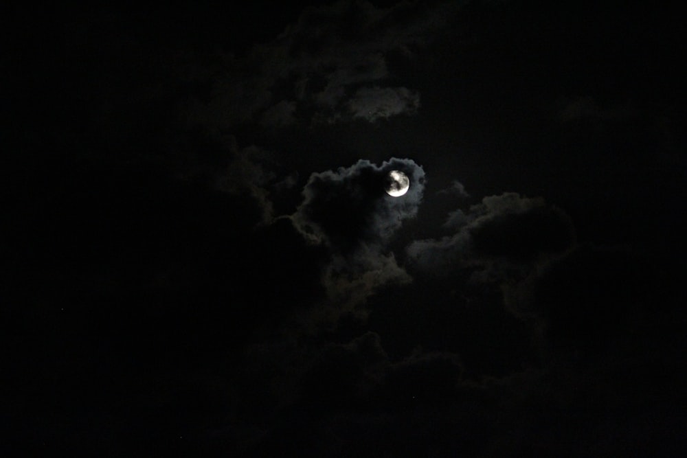 a full moon in the dark sky with clouds