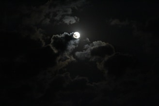 a full moon is seen through the clouds