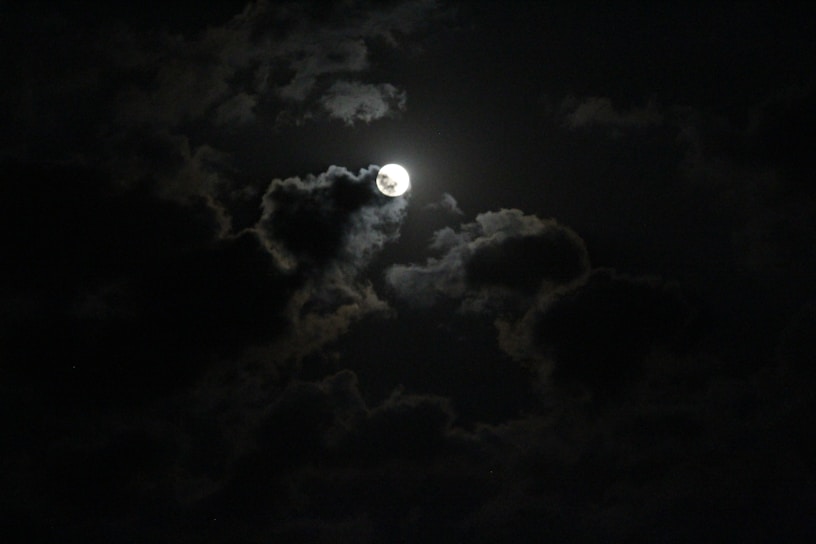 a full moon is seen through the clouds