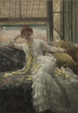A woman in a luxurious white dress with yellow ribbons lounges on a floral-patterned sofa. She gazes directly forward, resting her head on her hand. The background features a window view of a sandy beach with a couple of figures in the distance.