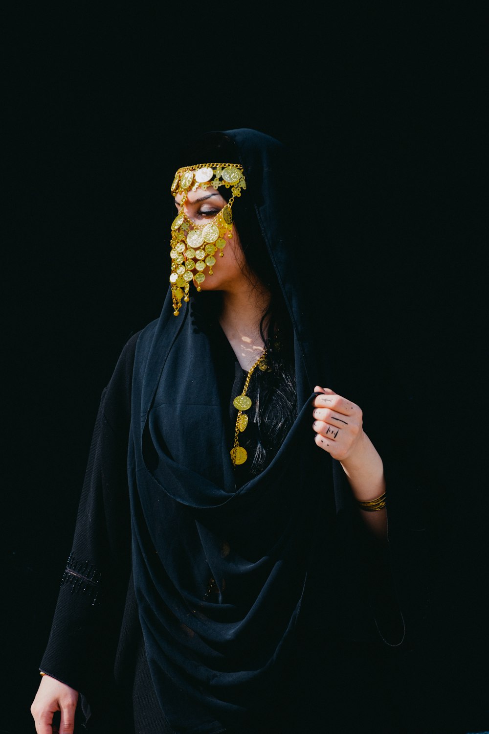 a woman wearing a black veil and gold jewelry