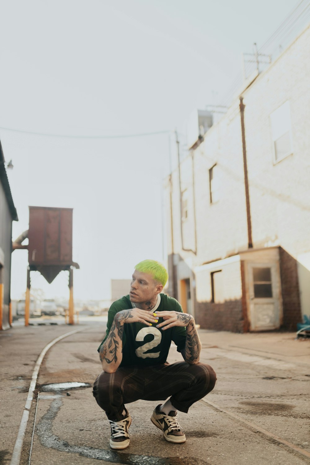 a man with green hair is squatting down