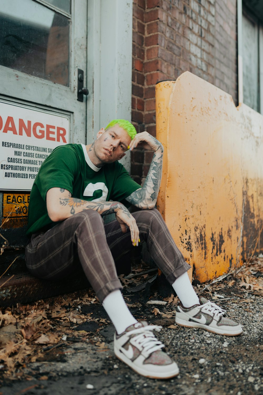 a man with green hair sitting on the ground