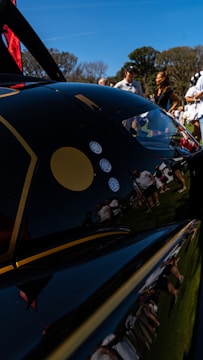 A consultant discussing car details with a client beside a parked vehicle outdoors.